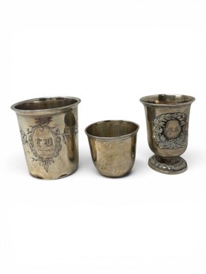 three silver cups with designs on them sitting next to each other