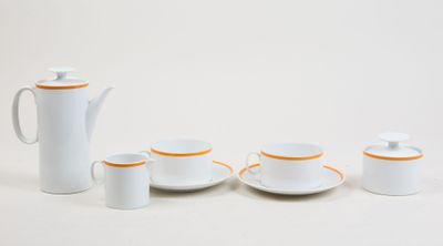 un service à thé blanc aux bords orange posé sur une table blanche