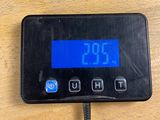 a digital clock on a wooden table with a black cord