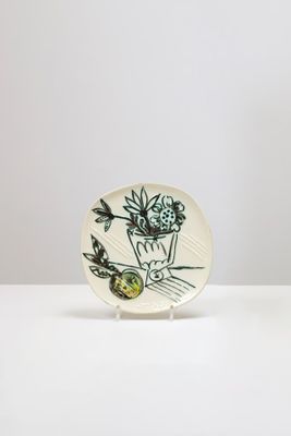 une assiette blanche ornée d'un motif floral noir et vert