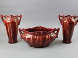 three red vases and a bowl sitting next to each other on a table