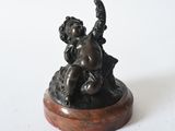 bronze figurine of a child on a rock holding a bird