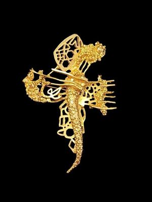 une image représentant une broche en forme de dragon doré sur fond noir