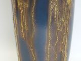 a blue vase with gold paint on it on a white surface