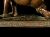 a bronze statue of a man bending over on a platform