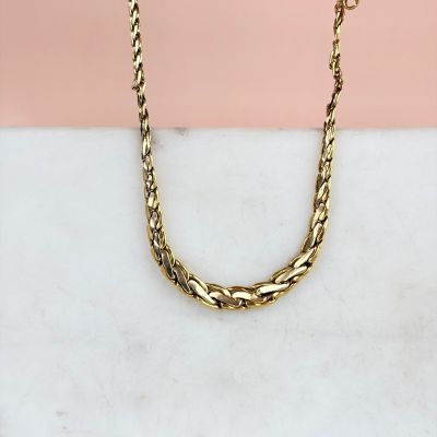 un gros plan d'un collier à chaîne en or posé sur une surface en marbre