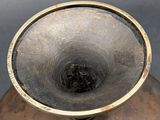 a large metal vase that has a hole in it