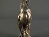silver statue of a dog on a rock on a gray background