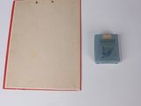 a piece of paper and a small box on a white surface