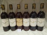six bottles of wine are lined up in a row on a table