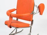 an orange leather rocking chair with a metal frame and arm rest