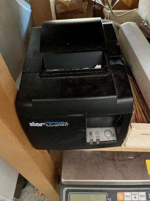 une imprimante noire posée sur une balance dans une pièce