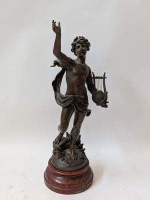 an antique bronze statue of a man holding a harp on a wooden base