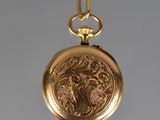 an antique gold pocket watch with a chain hanging from it ' s side