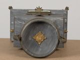 a silver clock sitting on top of a wooden table