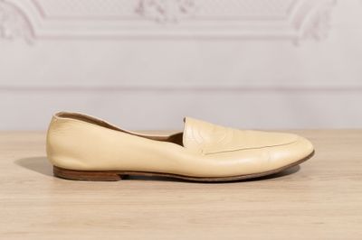 tan leather loafer shoes on a wooden table with a white wall in the background