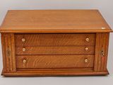 a small wooden chest with three drawers on top of it