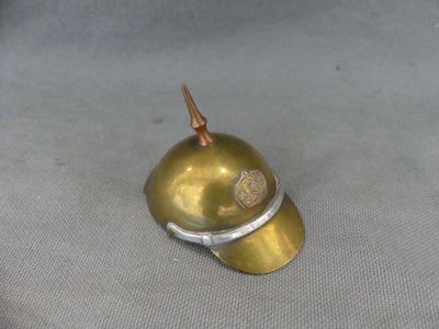 a small gold helmet with a metal handle on a gray surface