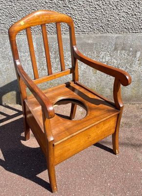 a wooden chair that has a toilet seat in it