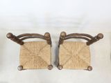 pair of wooden chairs with wicker seats on a white surface