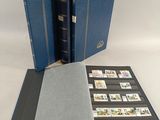 un livre bleu ouvert, orné de timbres, posé sur une table