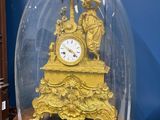 a gold clock under a glass dome on a table