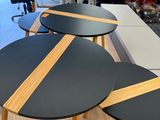 three black tables with wooden strips on top of them in a room