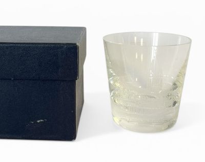 un verre d'eau posé à côté d'une boîte sur une surface blanche