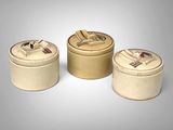 trois boîtes rondes munies d'un couvercle sont posées sur une surface grise
