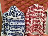 two sweaters sitting on top of a bed next to each other