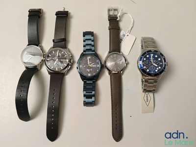 Quatre montres sont alignées sur une table, chacune munie d'une étiquette.