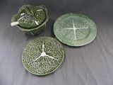 trois plats en céramique verts et blancs ornés de feuilles, posés sur une table