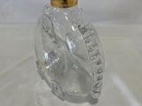 a clear glass bottle with a gold top on a white table