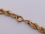 a close up of a gold chain bracelet on a white surface