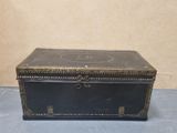 an old black leather trunk with brass hardware on the top