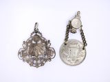 two silver pendants and a silver coin on a chain