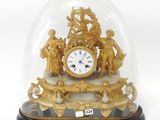 une horloge en or sous un dôme de verre sur une table