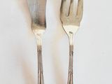 two forks and a knife on a white table