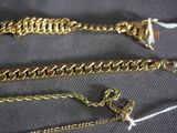 three different types of gold chains on a black cloth