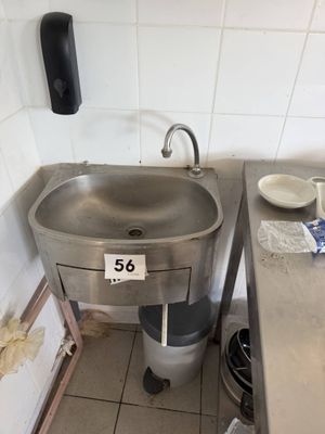 a sink in the corner of a kitchen with a lot of clutter on the counter