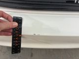 someone is measuring the height of the front bumper of a white car