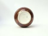 a brown and white vase sitting on a white surface