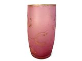 a pink vase with gold designs on it on a white surface