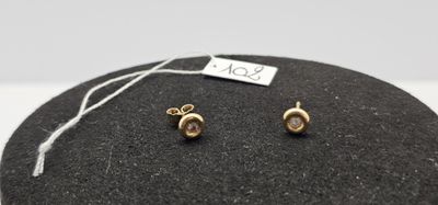 un gros plan sur une paire de boucles d'oreilles posées sur un rocher