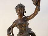 bronze statue of a woman holding a bird and a birdcage