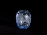 a glass vase with a leaf design on it on a black surface