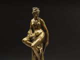 une statue en bronze représentant une femme assise sur un bloc de marbre