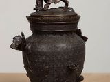 an old metal pot with a flower on top of it