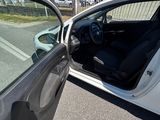 une voiture blanche dont la portière est ouverte, garée sur le bord de la route