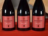 three bottles of wine sit on a red cloth next to a wooden crate